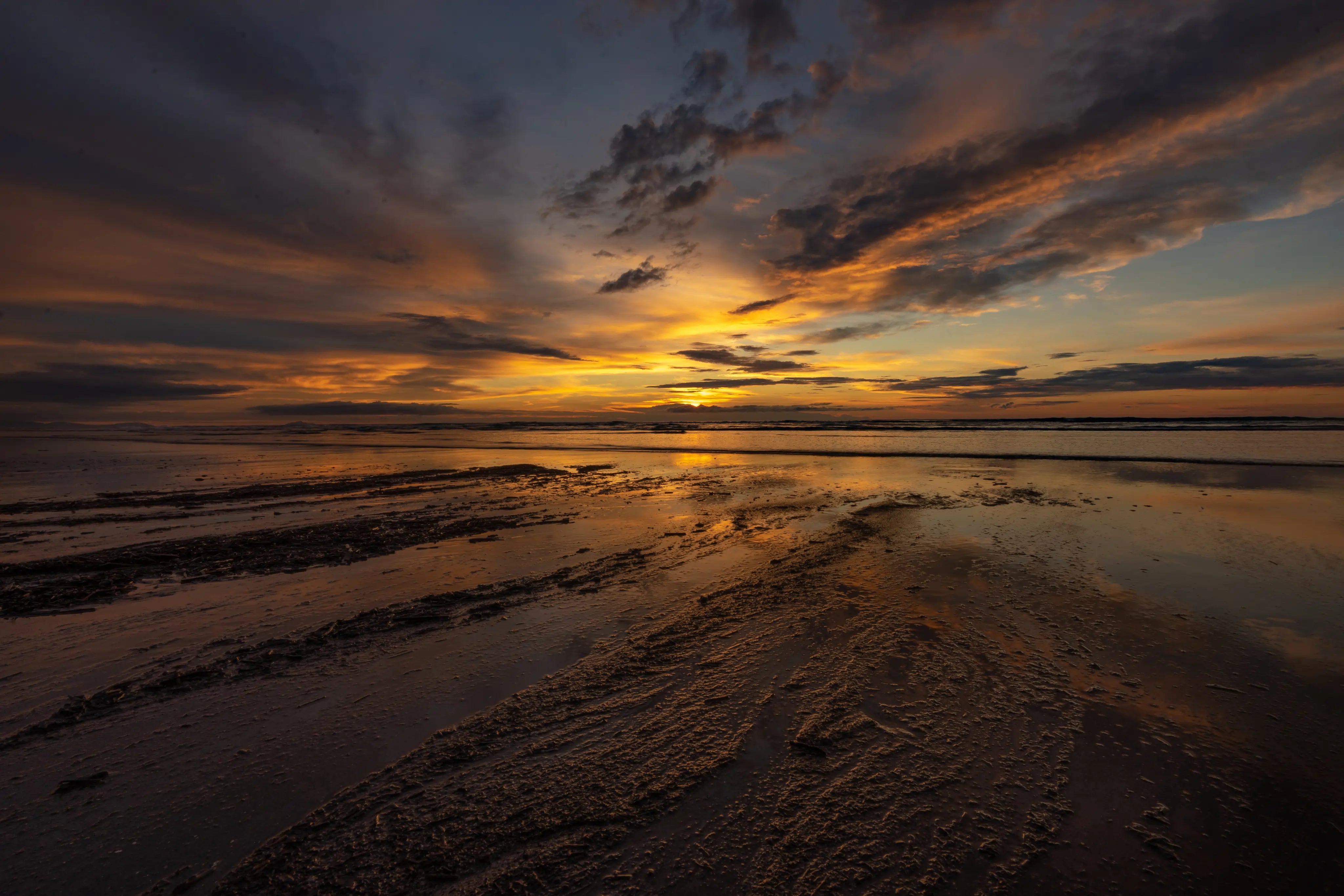 Colorful sunset reflected in wet and textured beach sand